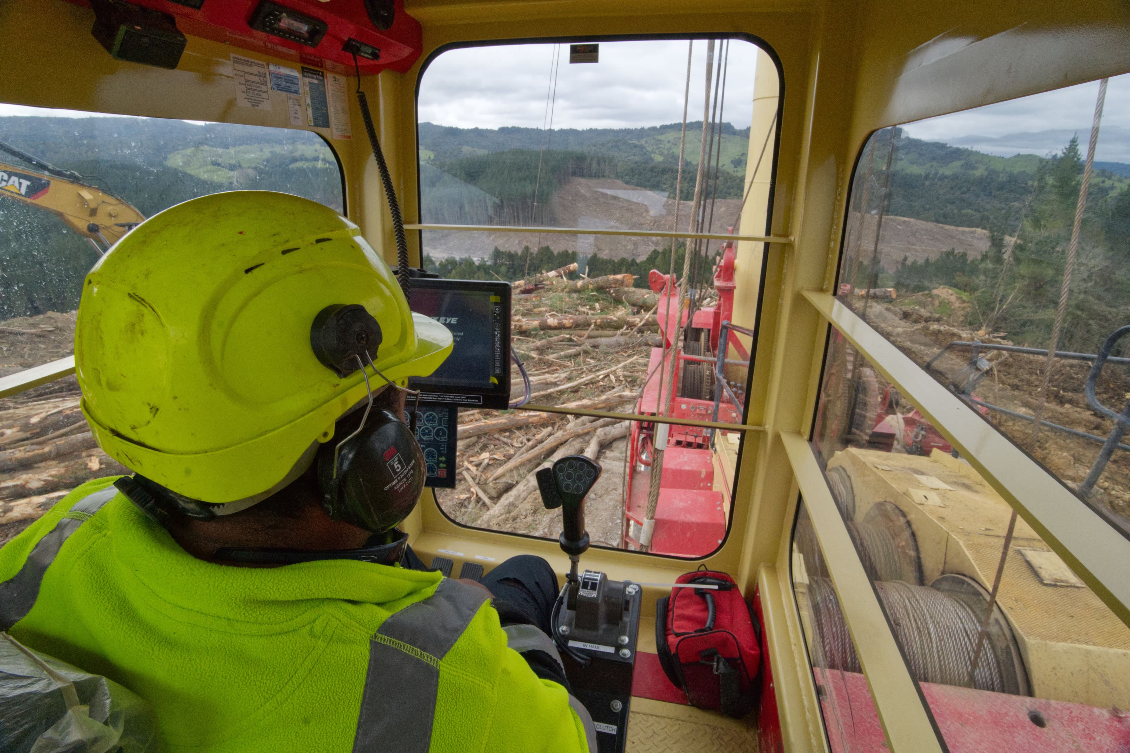 Person operating heavy machinery in lumber yard.